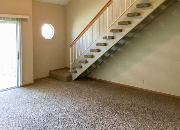 a living room with a staircase leading up to the loft