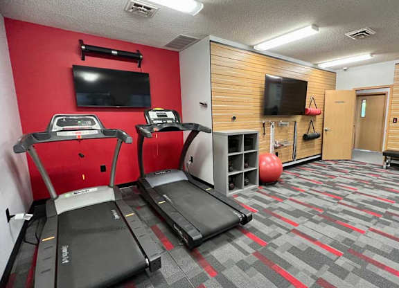 a 24-hour fitness center with treadmills, TVs, and yoga equipment.
