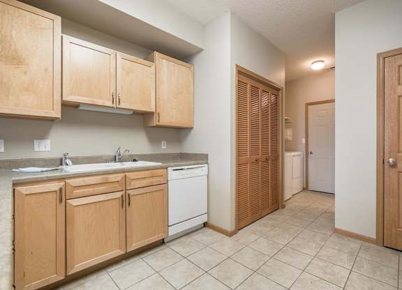 A kitchen with wooden cabinets and a white dishwasher.