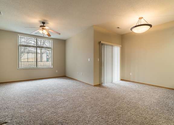 A room with a ceiling fan and carpeted floor.