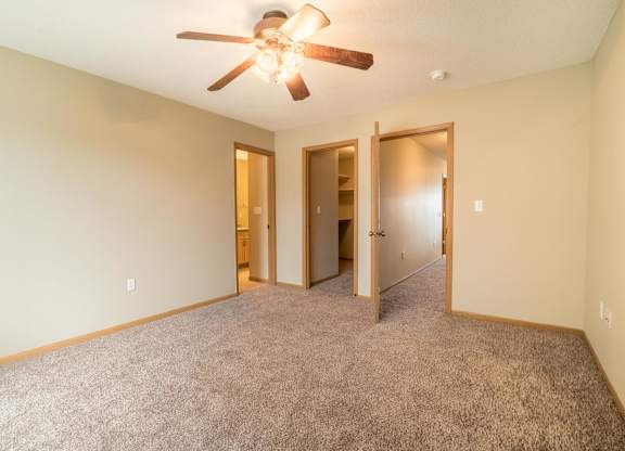 A room with a ceiling fan and carpeted floor.