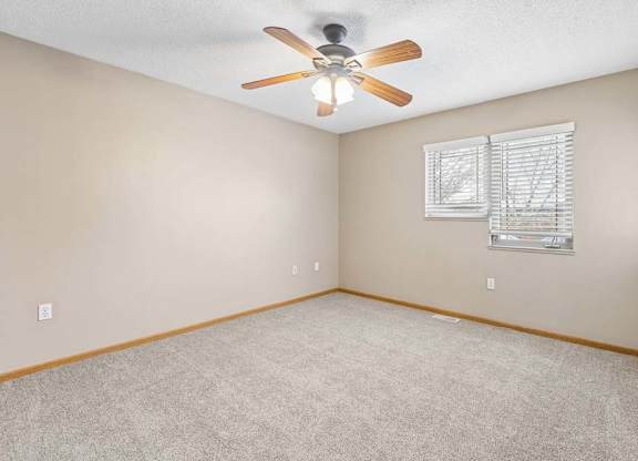Carpeted bedroom with ceiling fan and window.
