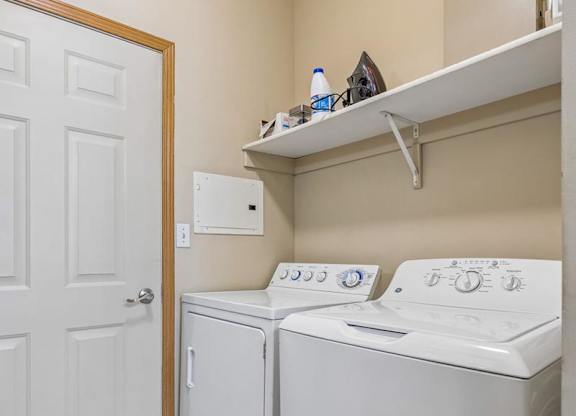 partment laundry room with full-size washer and dryer, shelving, and additional storage space.