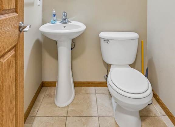 Apartment powder room with pedestal sink, framed mirror, neutral walls, and convenient main-level location.