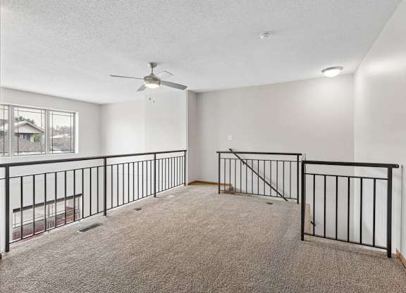 Spacious loft area overlooking the lower level with carpet and railing.
