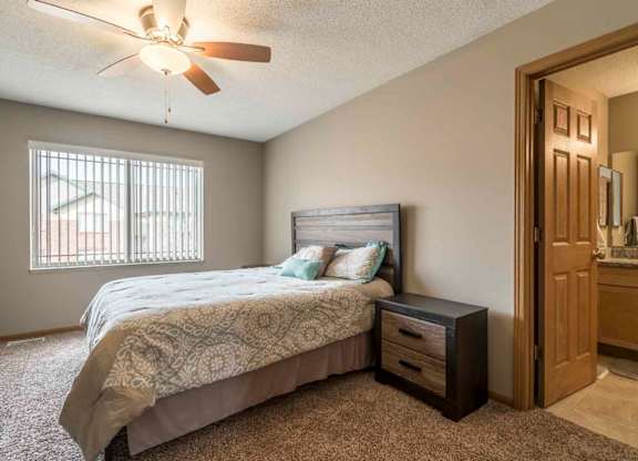 Master bedroom with attached bathroom and ceiling fan at Southwind Villas in southwest Omaha in La Vista, NE, 68128