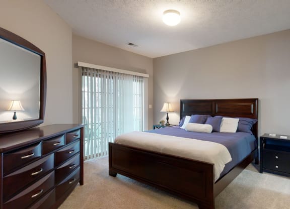 a bedroom with a bed and a dresser with large mirror on top