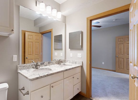 a bathroom with a vanity sink with granite counter top and a mirror with overhead lighting