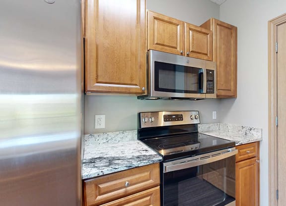 a kitchen with a stove and microwave and wooden cabinets and a granite countertop