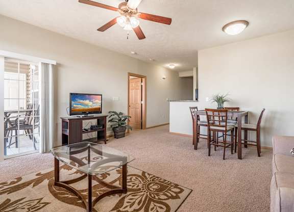 a living room and dining room with a table and a ceiling fan