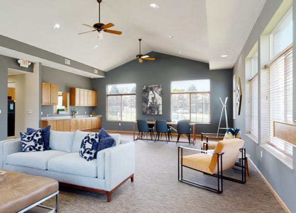 the clubhouse living room with gray walls, a stone fireplace, and seating