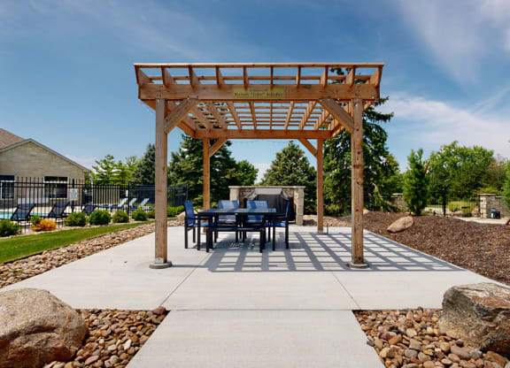 a table and chairs under a wooden pergola