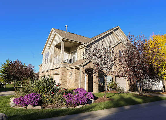 the front of a villa building with a yard with purple flowers