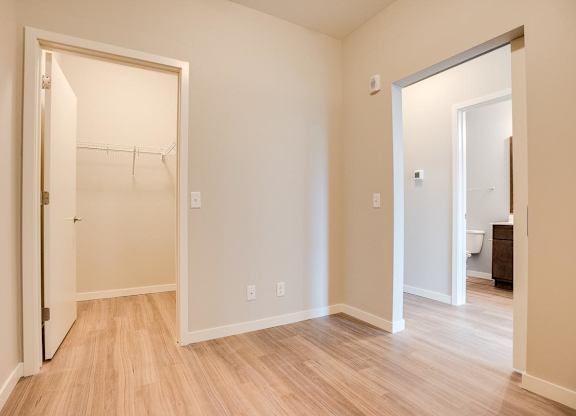 A room with doors to a walk-in closet and hallway