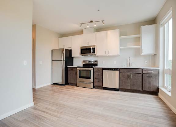 A kitchen with a refrigerator, microwave, oven, and cabinets.