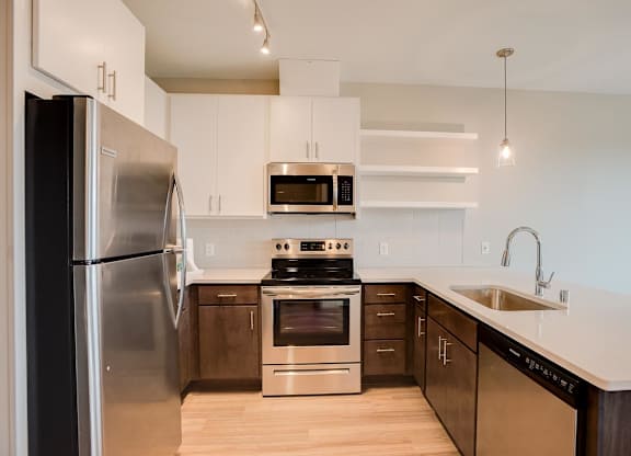 A modern kitchen with a stainless steel refrigerator and a stove top oven.