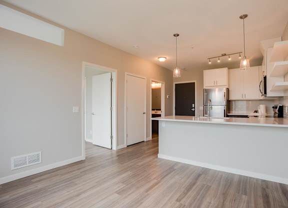 A kitchen with a white counter and wooden floors.