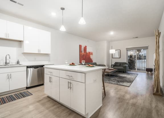 Contemporary design scheme with white kitchen cabinetry, quartz countertops and open layout at The Conrad