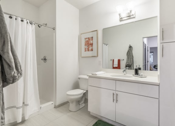 Contemporary bathroom with white cabinetry and white quartz countertops at The Conrad