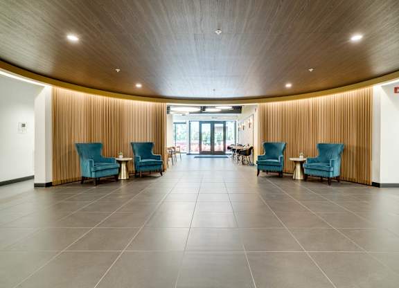 An open apartment lobby with blue chairs and a wooden ceiling.