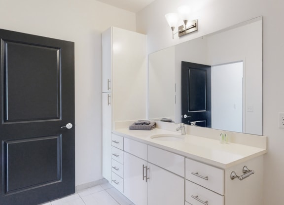 Furnished apartment bathroom with large white vanity and left side storage cabinet
