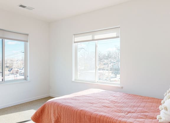 Furnished apartment bedroom with a large window on each wall