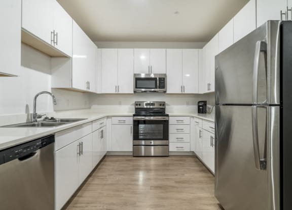 Contemporary kitchen with white cabinetry, quartz countertops and stainless steel appliances at The Conrad