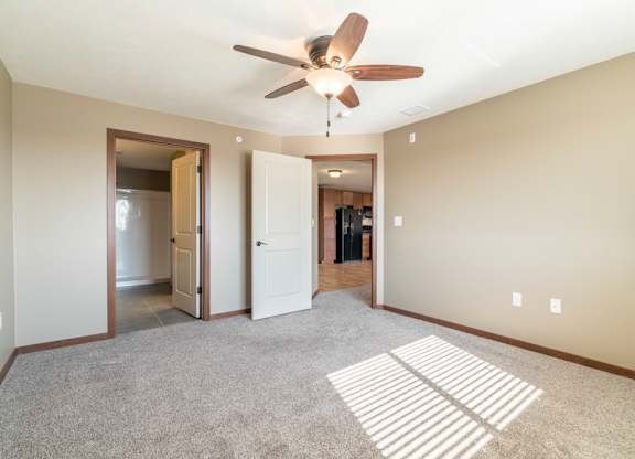 A room with a ceiling fan and carpeted floor.