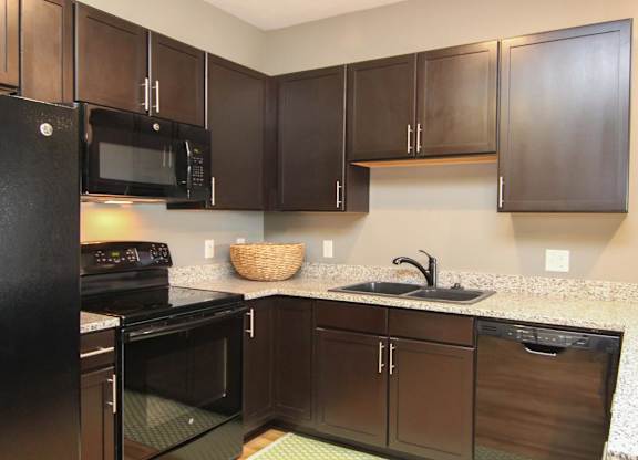 A kitchen with black appliances and brown cabinets.