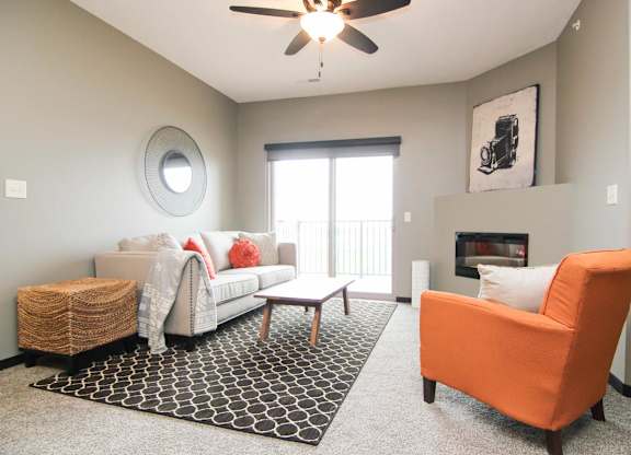 A living room with a white couch, a black and white rug, and an orange chair.