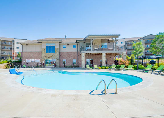our resort style swimming pool with green lounge chairs