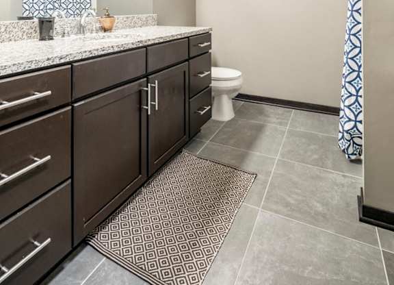 Bathroom with granite countertops and tile flooring at The Flats at 84 in southeast Lincoln NE 68516