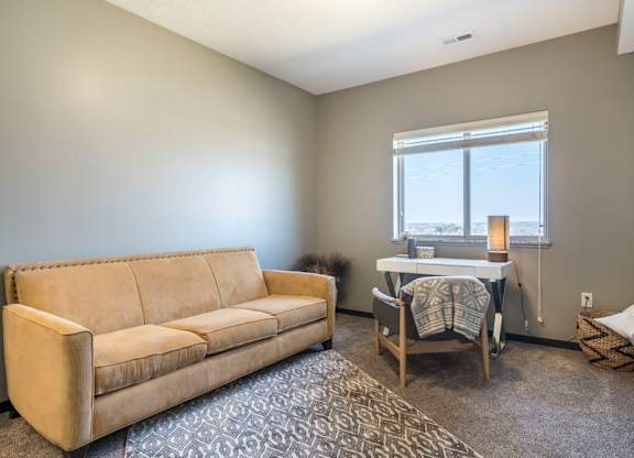 A tan couch sits in a room with a table and chairs.
