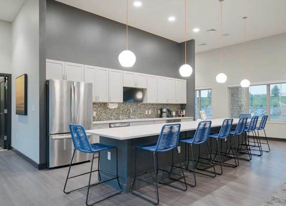 Modern resident lounge kitchen with expansive island seating, white cabinets, mosaic tile backsplash, and contemporary finishes.
