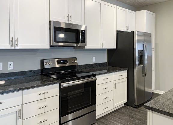 White cabinetry and matching stainless steel appliances in the kitchen of the buffalo floorplan at the flats at shadow creek