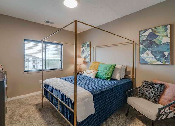 a bedroom with a bed and a chair and a window