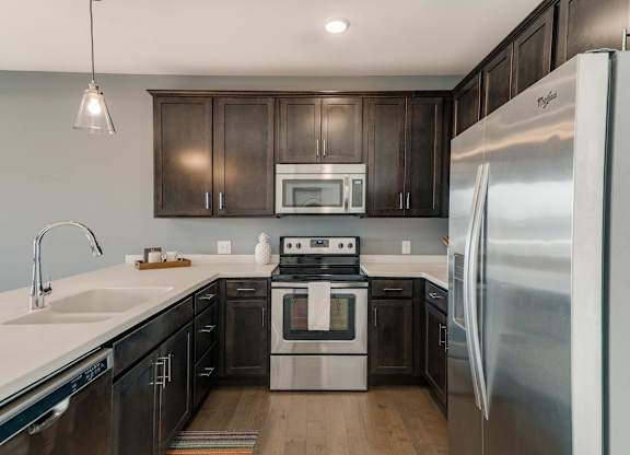 A modern kitchen with dark wood cabinets and stainless steel appliances.