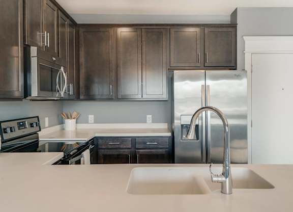 A modern kitchen with dark brown cabinets and stainless steel appliances.