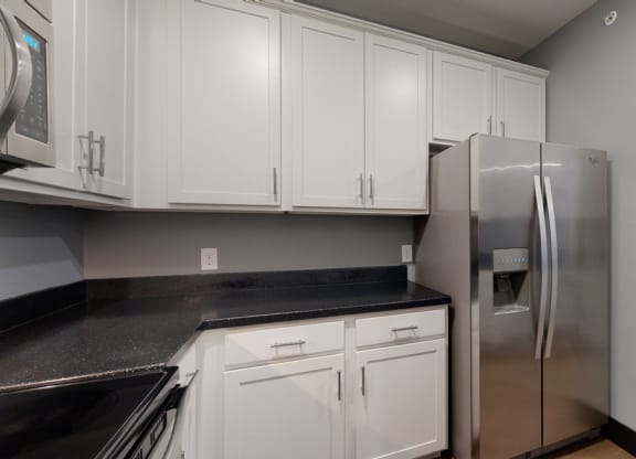 a kitchen with white cabinets and a stainless steel refrigerator