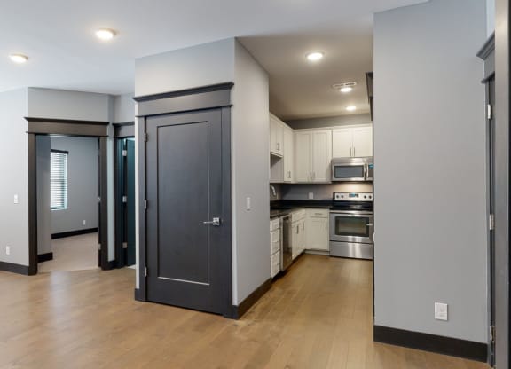 a kitchen and living room with a hardwood floor and grey walls