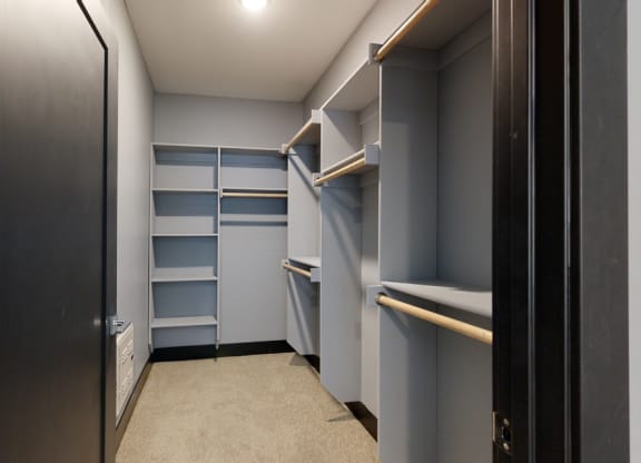 a walk in closet with gray walls and shelves