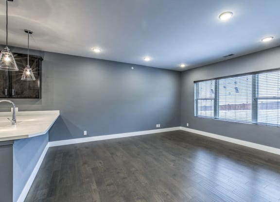Large living space with hardwood-style flooring and large windows providing natural light at The Helen