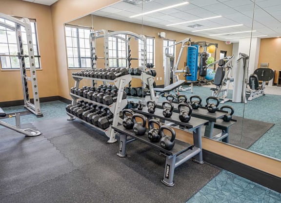 a fitness center tith two racks of free weights in front of a mirrored wall