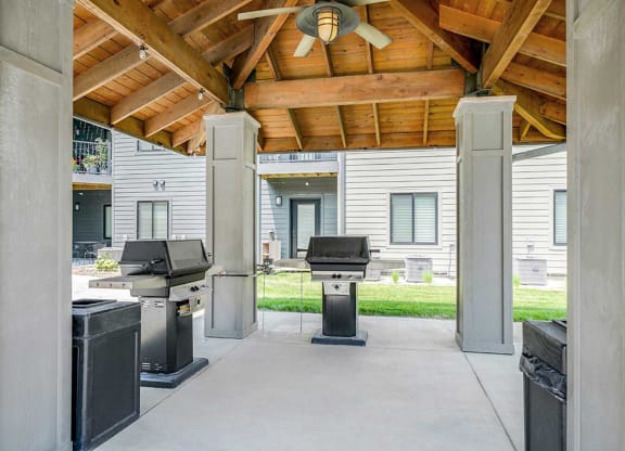 a covered outdoor grill station with two grills and a ceiling fan