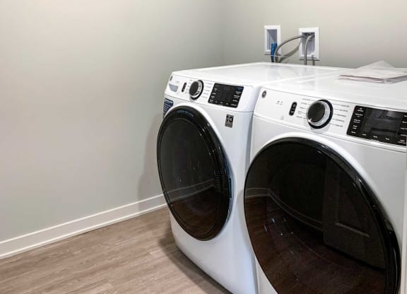 a washer and dryer in a laundry room with a wooden floor