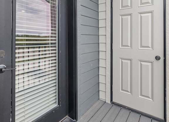 Apartment balcony with private storage closet, gray siding, and wood-look decking.