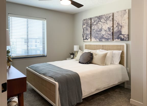 Furnished bedroom with ceiling fan and marbled art above the bed
