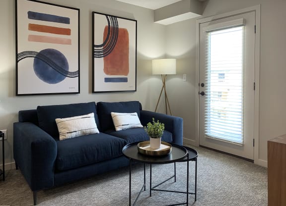 a living room with a blue couch and two paintings on the wall