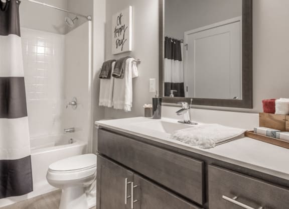 Interiors- Bathroom with dark cabinets and white, cultured-marble countertops at The Preserve at Normandale Lake