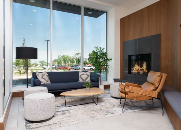 Lounging space with seating next to a fireplace and large floor to ceiling window.